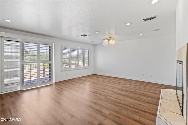 unfurnished living room with wood-type flooring and a textured ceiling