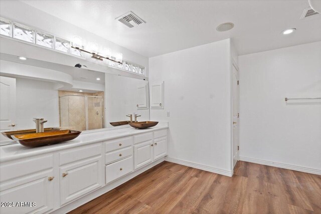 bathroom with wood-type flooring, a shower with door, and vanity