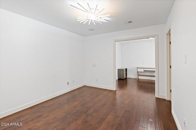 unfurnished room featuring dark wood-type flooring and a chandelier