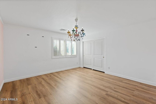 empty room with a chandelier and light hardwood / wood-style floors