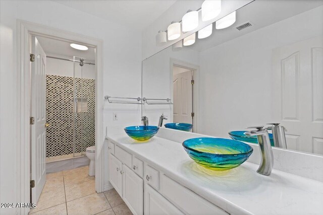 bathroom with a shower with door, toilet, vanity, and tile patterned floors