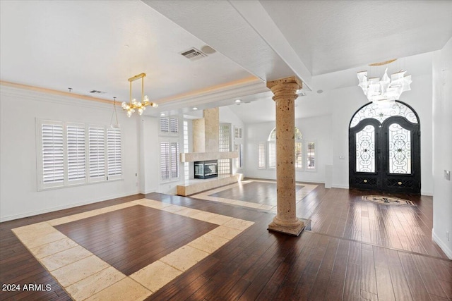 entrance foyer with a notable chandelier, dark hardwood / wood-style floors, and decorative columns