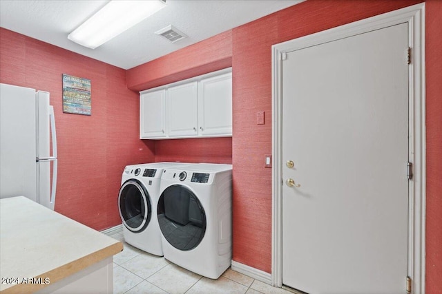 laundry area featuring washer and dryer, light tile patterned floors, and cabinets