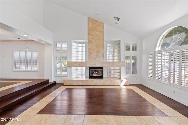 unfurnished living room featuring wood-type flooring, plenty of natural light, a premium fireplace, and high vaulted ceiling