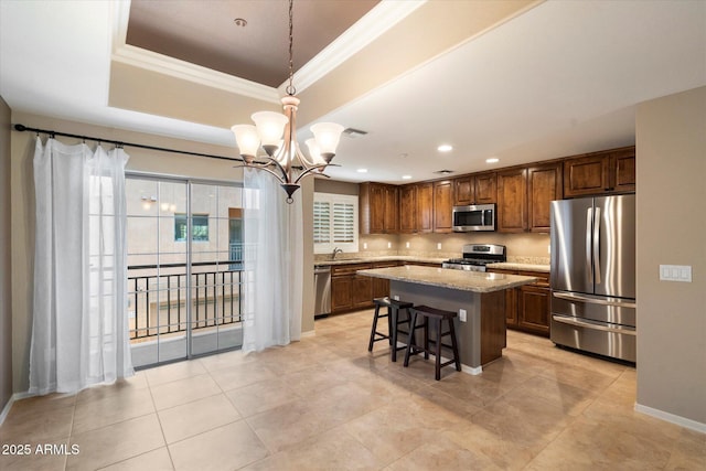 kitchen featuring a center island, decorative light fixtures, stainless steel appliances, sink, and light stone counters