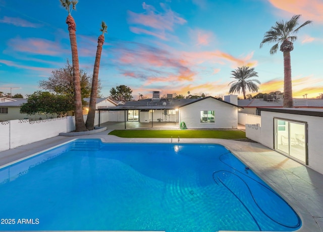 pool at dusk featuring a patio