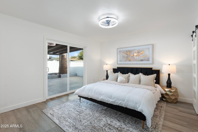 bedroom featuring access to exterior, light hardwood / wood-style floors, and a barn door