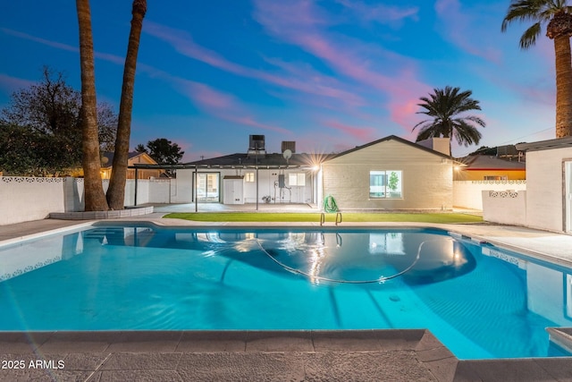 pool at dusk with a patio area