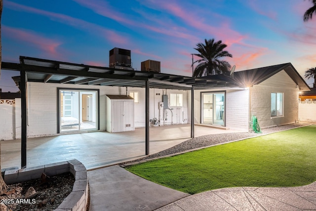 back house at dusk with cooling unit, a yard, and a patio area