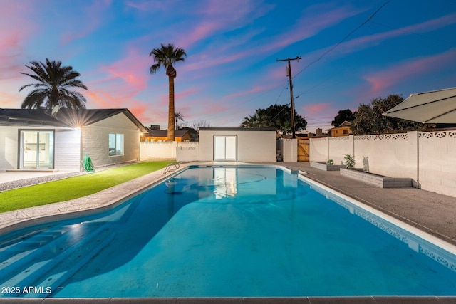 pool at dusk featuring an outdoor structure and a patio