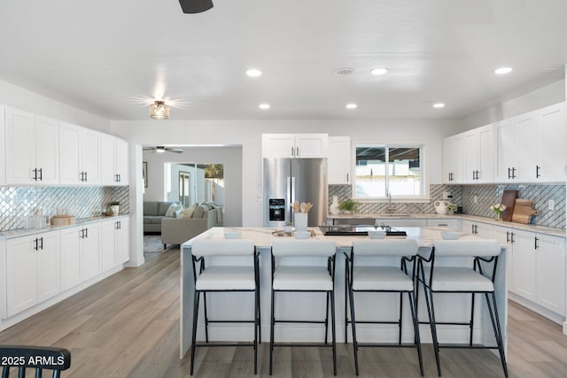 kitchen featuring stainless steel fridge, a breakfast bar area, and white cabinets