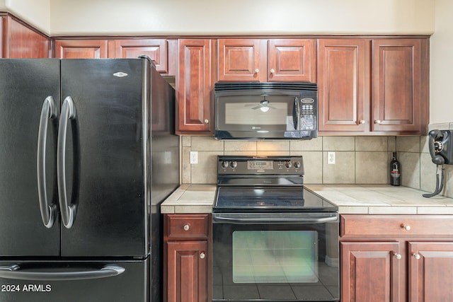 kitchen featuring decorative backsplash, tile counters, and black appliances