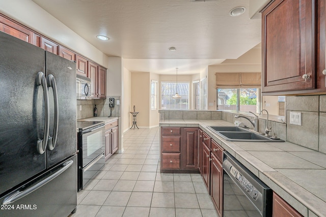 kitchen featuring tasteful backsplash, sink, black appliances, pendant lighting, and tile counters