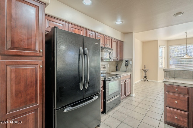 kitchen with backsplash, stainless steel appliances, hanging light fixtures, tile counters, and light tile patterned flooring