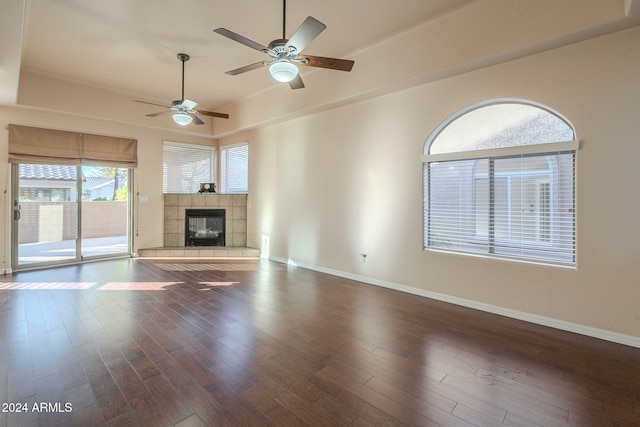 unfurnished living room with a tiled fireplace, ceiling fan, and dark hardwood / wood-style floors