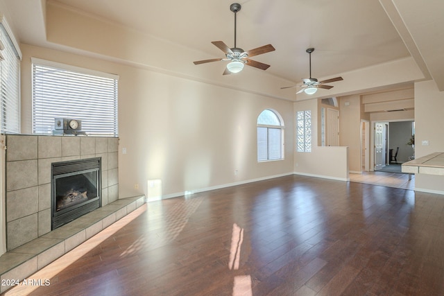 unfurnished living room with dark hardwood / wood-style floors, ceiling fan, and a tiled fireplace