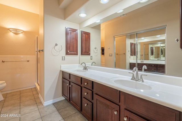 bathroom featuring tile patterned flooring, vanity, toilet, and a shower with shower door