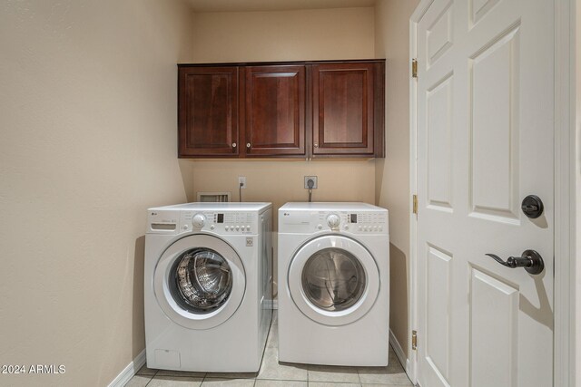 laundry area with cabinets, light tile patterned floors, and washing machine and dryer