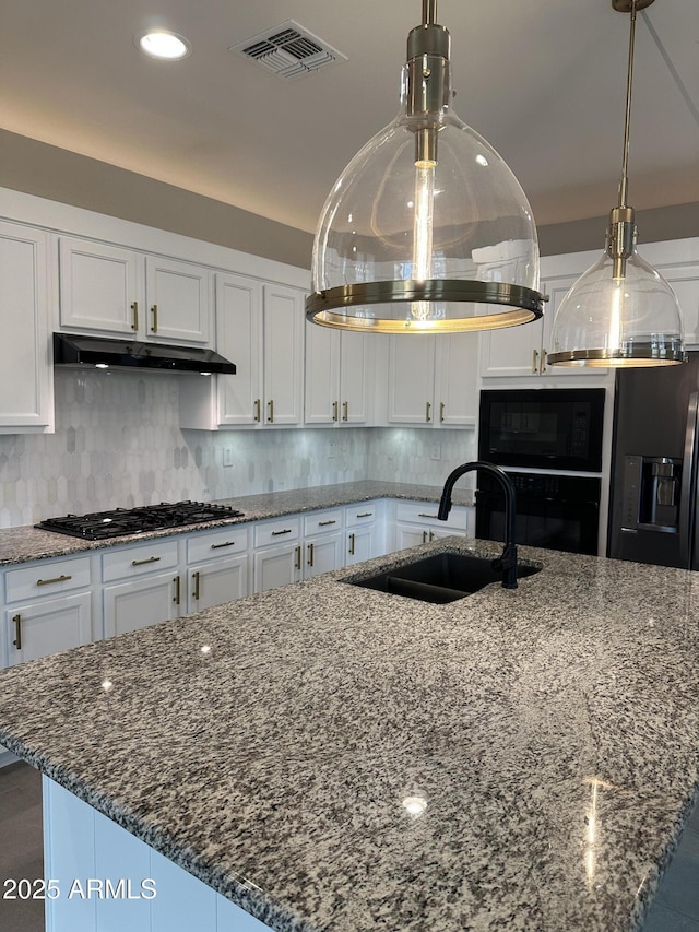 kitchen with visible vents, dark stone counters, black appliances, under cabinet range hood, and white cabinetry