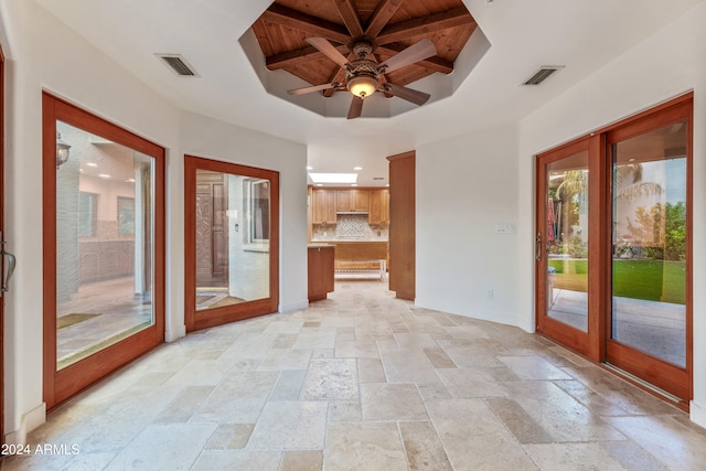 interior space with beam ceiling, ceiling fan, french doors, a raised ceiling, and wood ceiling