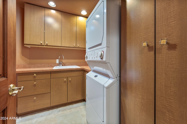 washroom featuring cabinets, stacked washer / dryer, sink, and light tile patterned floors