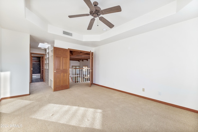 carpeted empty room featuring a raised ceiling and ceiling fan