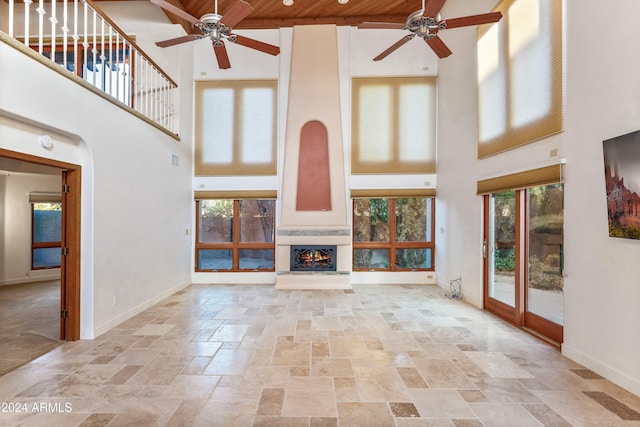 unfurnished living room with ceiling fan, wood ceiling, and a high ceiling