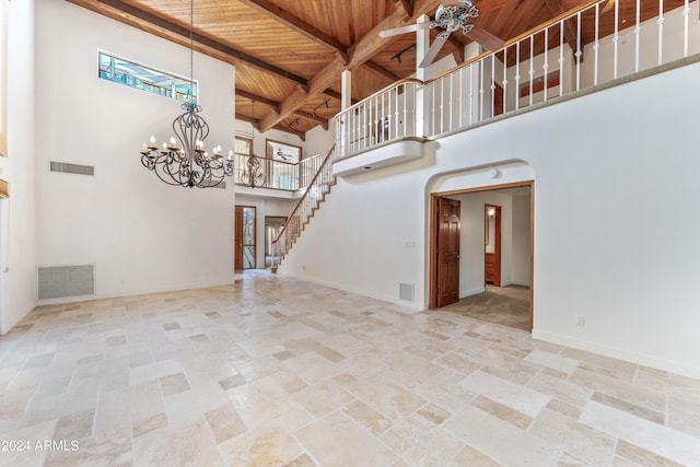 unfurnished living room featuring beamed ceiling, ceiling fan with notable chandelier, wood ceiling, and a high ceiling