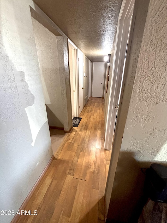 520 W Rocalla Ave, Ajo, AZ 85321 - hallway featuring baseboards, light wood finished floors, a textured wall, and a textured ceiling