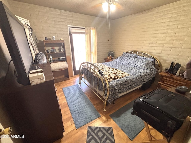 520 W Rocalla Ave, Ajo, AZ 85321 - bedroom featuring ceiling fan, wood finished floors, brick wall, and a textured ceiling