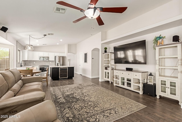 living room featuring visible vents, a ceiling fan, dark wood-style floors, and wine cooler