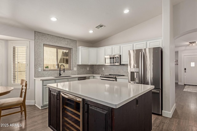 kitchen with stainless steel appliances, a sink, visible vents, light countertops, and beverage cooler