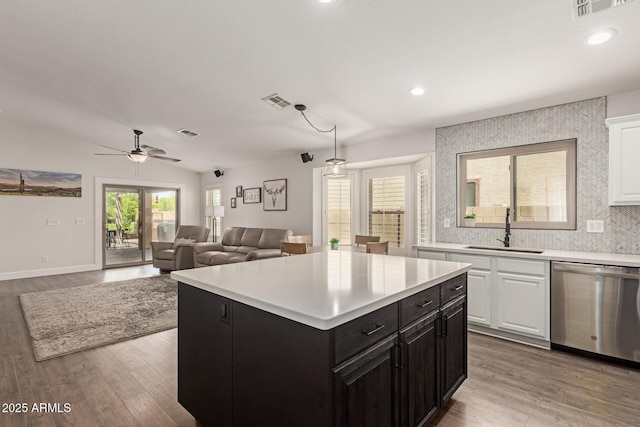 kitchen featuring white cabinets, light countertops, dishwasher, and a sink