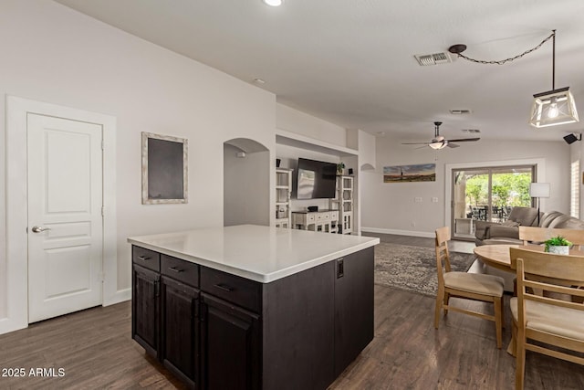 kitchen featuring visible vents, a ceiling fan, arched walkways, open floor plan, and dark wood-style flooring