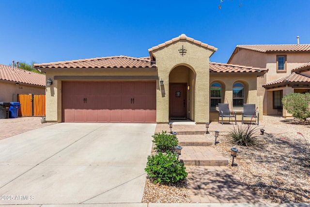 mediterranean / spanish home with a garage, driveway, a tiled roof, and stucco siding