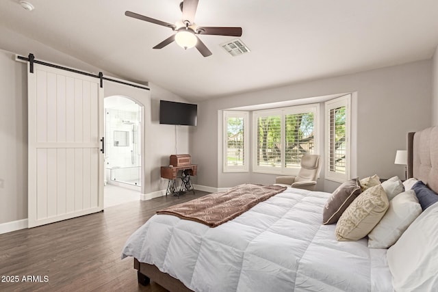 bedroom featuring a barn door, wood finished floors, ensuite bath, lofted ceiling, and visible vents