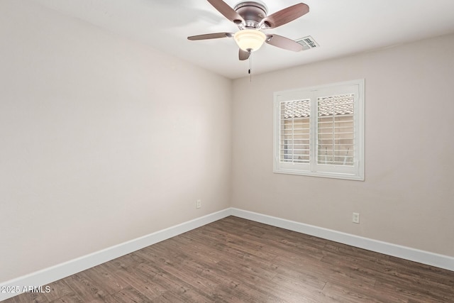 unfurnished room with baseboards, a ceiling fan, dark wood-type flooring, and visible vents