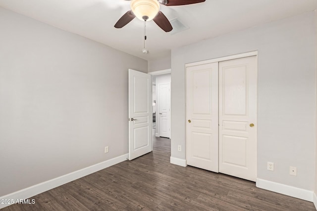 unfurnished bedroom featuring visible vents, baseboards, dark wood-type flooring, and a closet