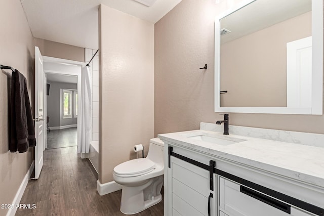 full bathroom with toilet, vanity, wood finished floors, and baseboards