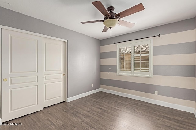 unfurnished bedroom featuring wood finished floors, baseboards, a closet, and ceiling fan