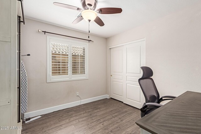 unfurnished office with baseboards, a ceiling fan, and wood finished floors