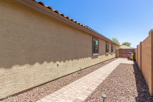 view of side of home with a fenced backyard and stucco siding