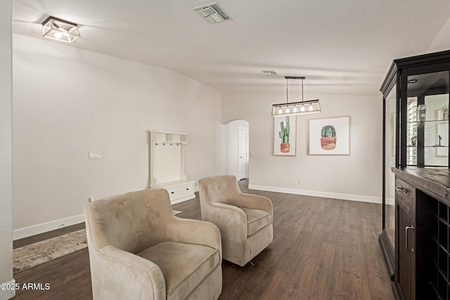 living area with arched walkways, visible vents, baseboards, and dark wood-style flooring