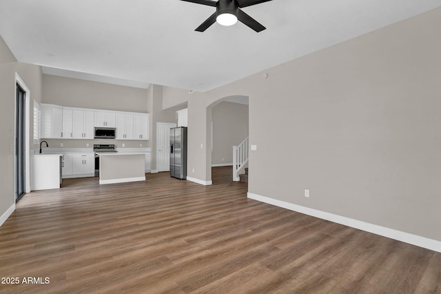 3376 E Lafayette Ave, Gilbert, AZ 85298 - unfurnished living room featuring ceiling fan, arched walkways, wood finished floors, and stairs