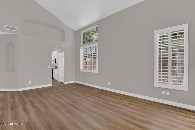 3376 E Lafayette Ave, Gilbert, AZ 85298 - unfurnished living room featuring healthy amount of natural light, high vaulted ceiling, wood finished floors, and arched walkways
