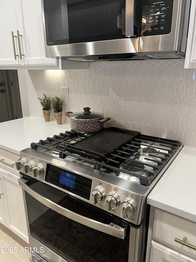 kitchen with stainless steel appliances, white cabinetry, and tasteful backsplash