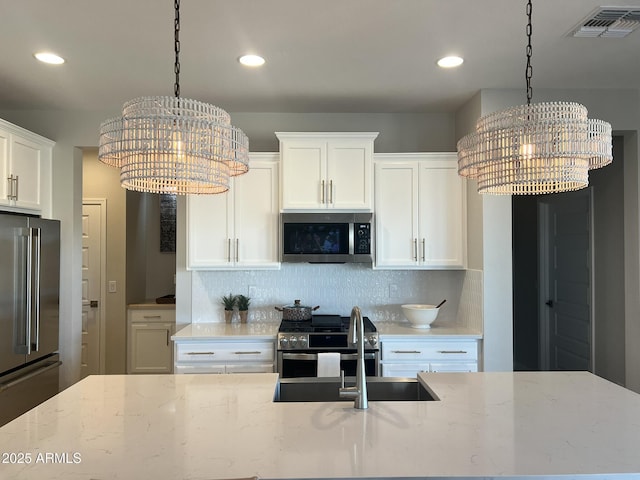 kitchen with white cabinetry, light stone countertops, a chandelier, and appliances with stainless steel finishes