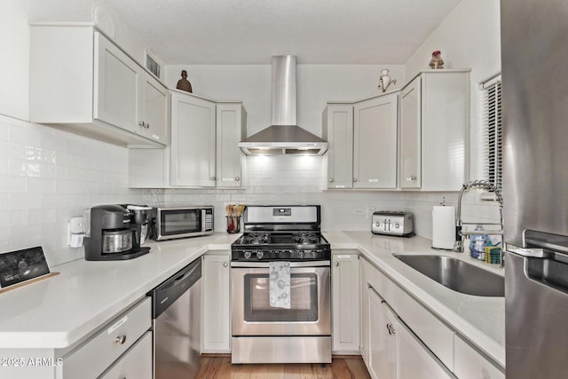 kitchen with white cabinetry, wall chimney range hood, and stainless steel appliances