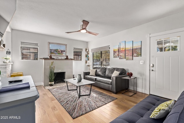 living room with a textured ceiling, light hardwood / wood-style flooring, and ceiling fan