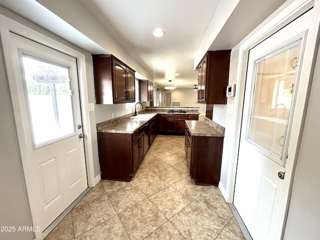 kitchen featuring recessed lighting, light tile patterned floors, a sink, baseboards, and dark brown cabinetry